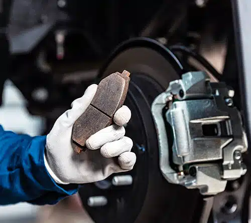Mechanic showing worn out brake pad.